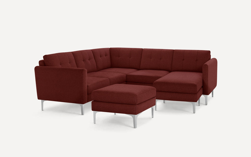 Modern L-shaped sectional sofa in deep red fabric with tufted back cushions and a matching ottoman, supported by sleek silver legs.