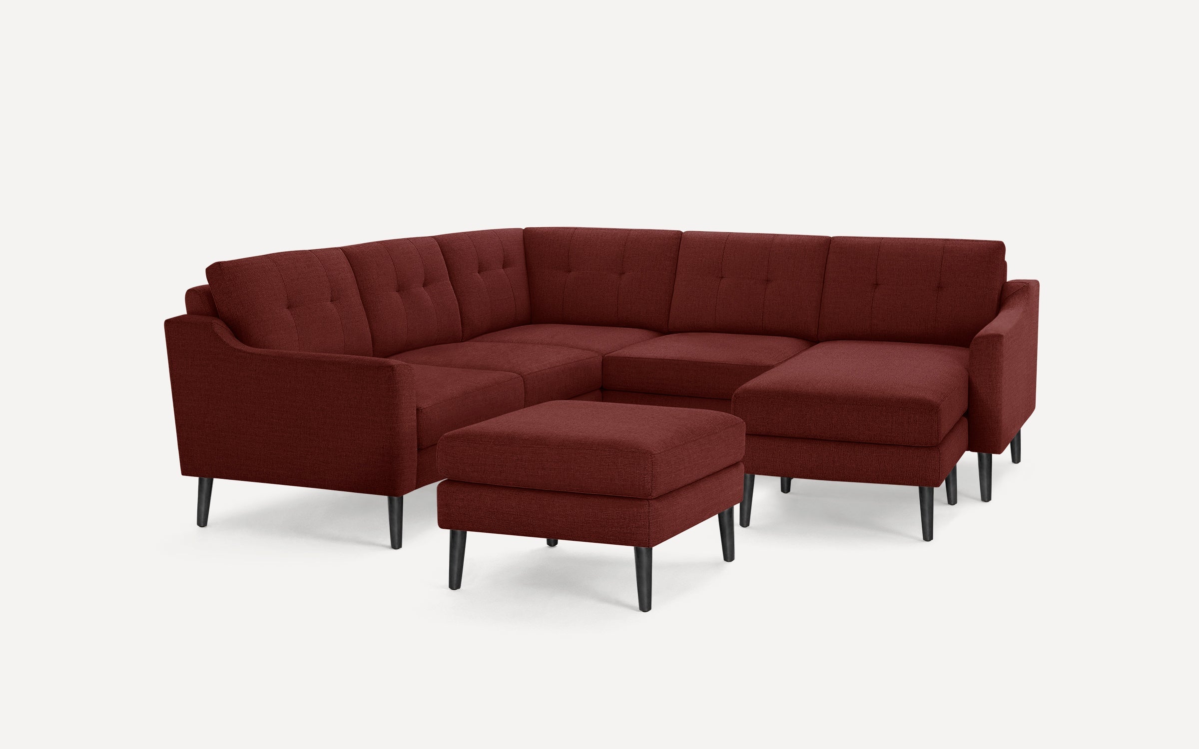 Modern burgundy fabric sectional sofa with button-tufted back cushions, black tapered legs, and matching ottoman, arranged in an L-shape.