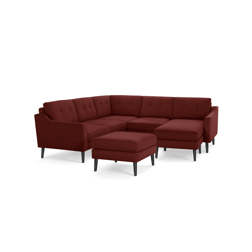 Modern sectional sofa with deep red fabric upholstery, button-tufted cushions, black tapered legs, and a matching ottoman.