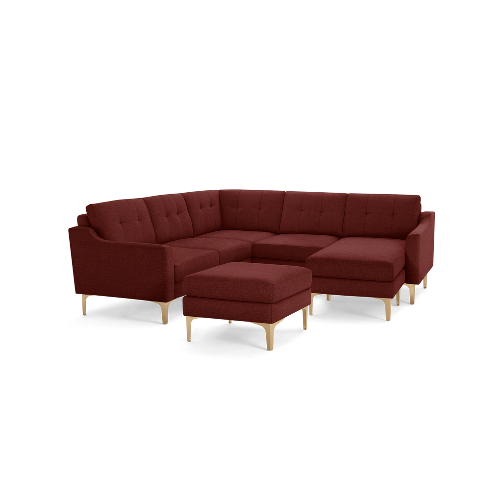 Modern L-shaped sectional sofa in dark red upholstery with tufted cushions and light wooden legs, includes matching ottoman.