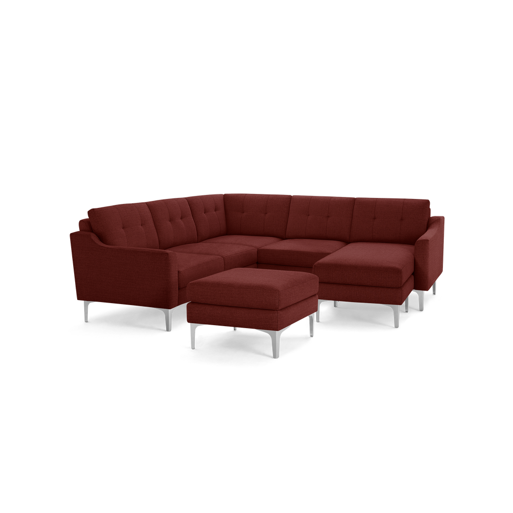 Modern L-shaped sectional sofa in deep red fabric with tufted cushions, featuring slim metallic legs and a matching ottoman.
