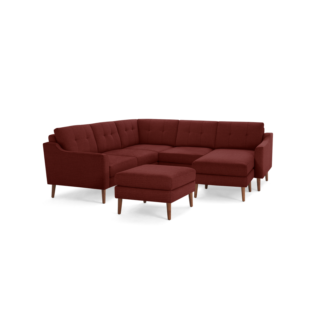 Modern L-shaped sectional sofa in deep red fabric, featuring tufted back cushions and wooden legs, with matching ottoman.