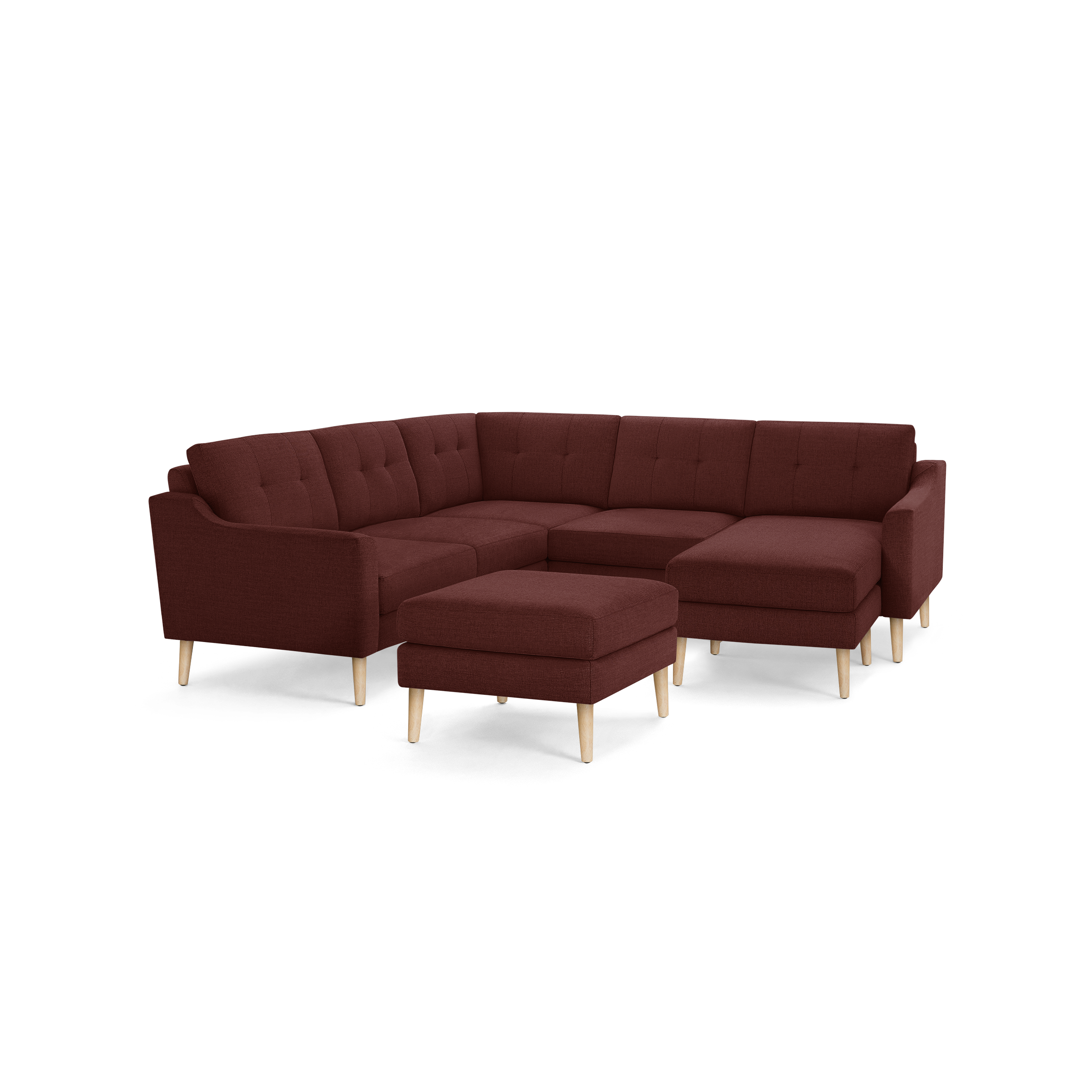 Modern sectional sofa in deep red fabric with tufted back cushions and light wooden legs, accompanied by a matching ottoman.