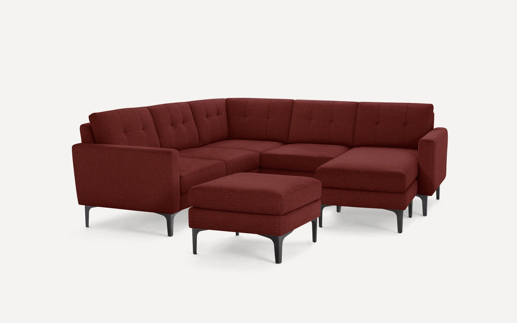 Modern L-shaped sectional sofa with deep red fabric upholstery and matching cushioned ottoman, featuring black tapered legs.