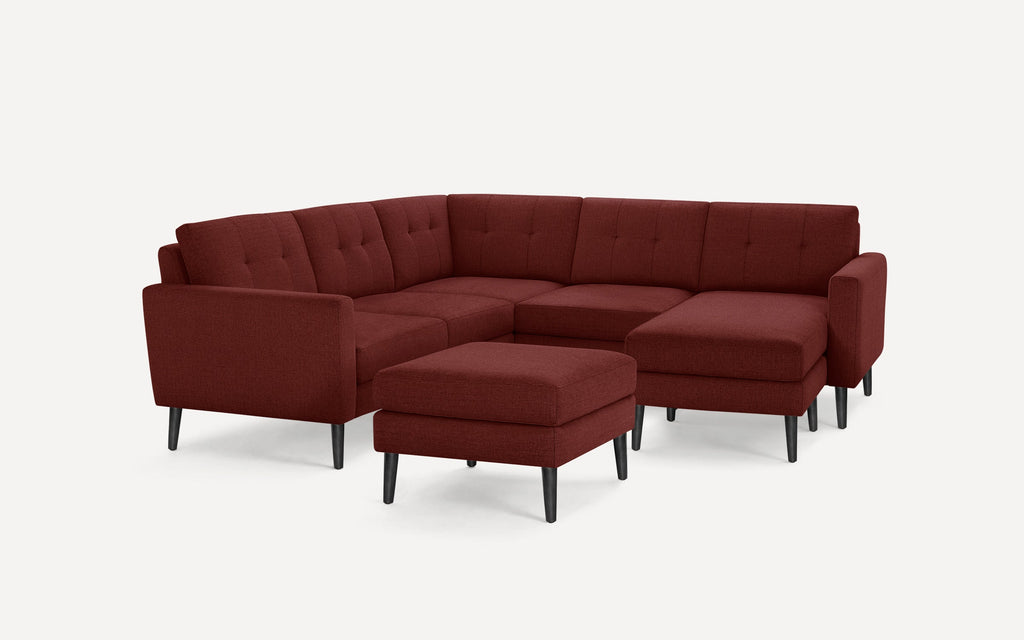 Modern sectional sofa in deep red fabric with tufted cushions and black tapered legs, including matching ottoman.