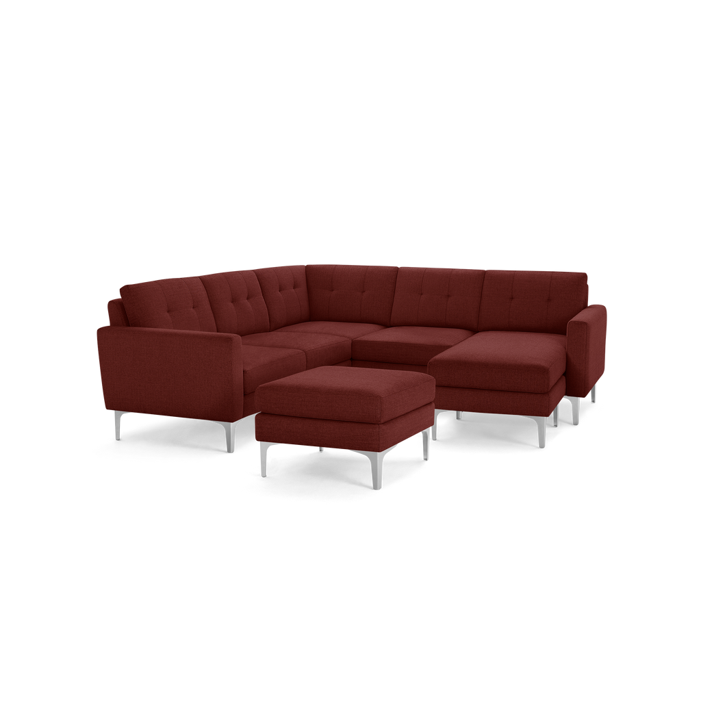 Modern L-shaped sectional sofa in dark red fabric with tufted back cushions and matching ottoman, supported by silver metal legs.