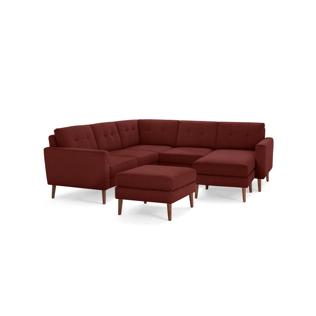 Modern L-shaped sectional sofa with tufted back cushions and matching ottoman, upholstered in deep red fabric with wooden legs.