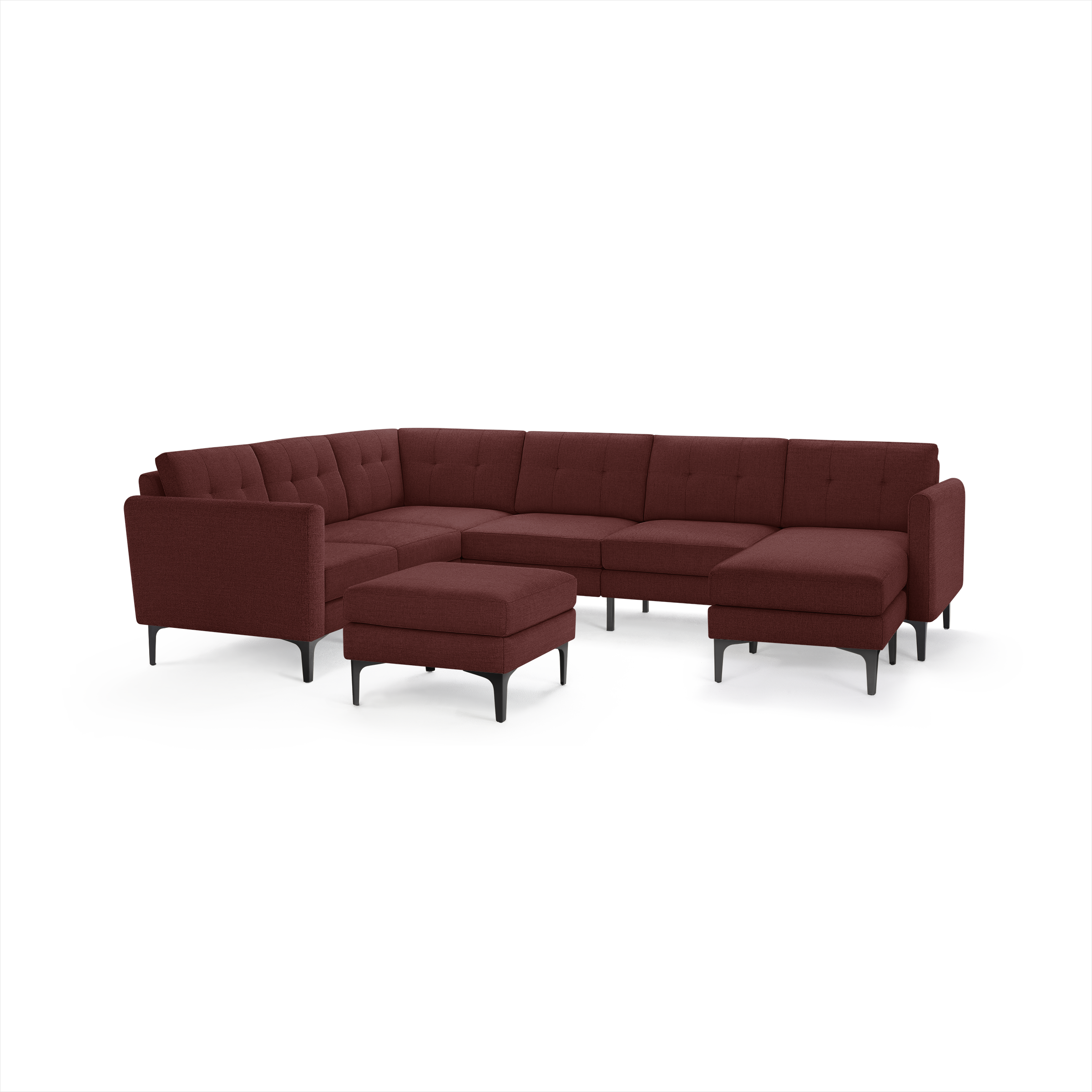 Large modern sectional sofa in deep red fabric with tufted back cushions and matching ottoman on black legs.