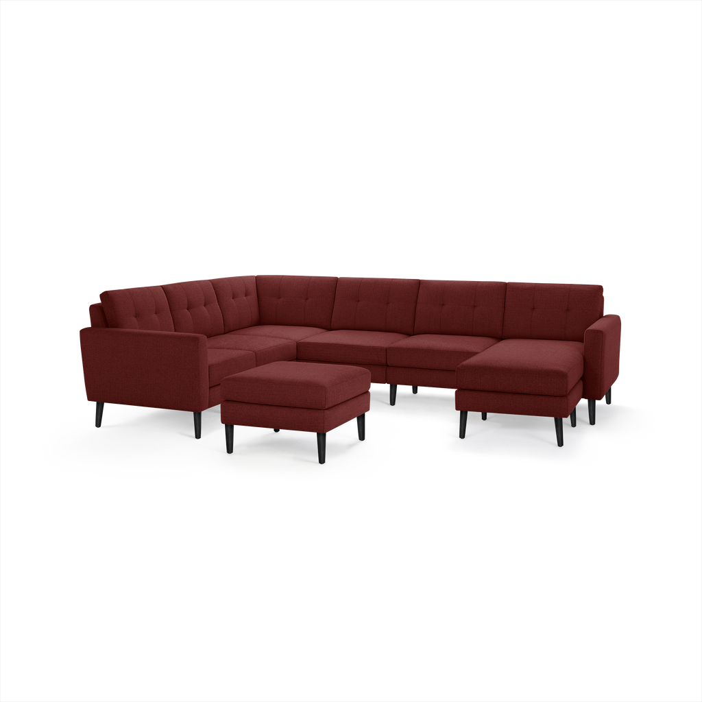 Large modern sectional sofa in deep red fabric with tufted back cushions and matching ottoman, supported by black tapered legs.