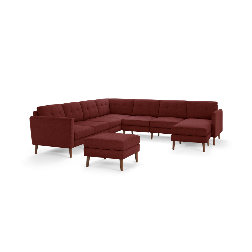 Modern L-shaped sectional sofa in deep red fabric with tufted cushions, wooden legs, and a matching ottoman.
