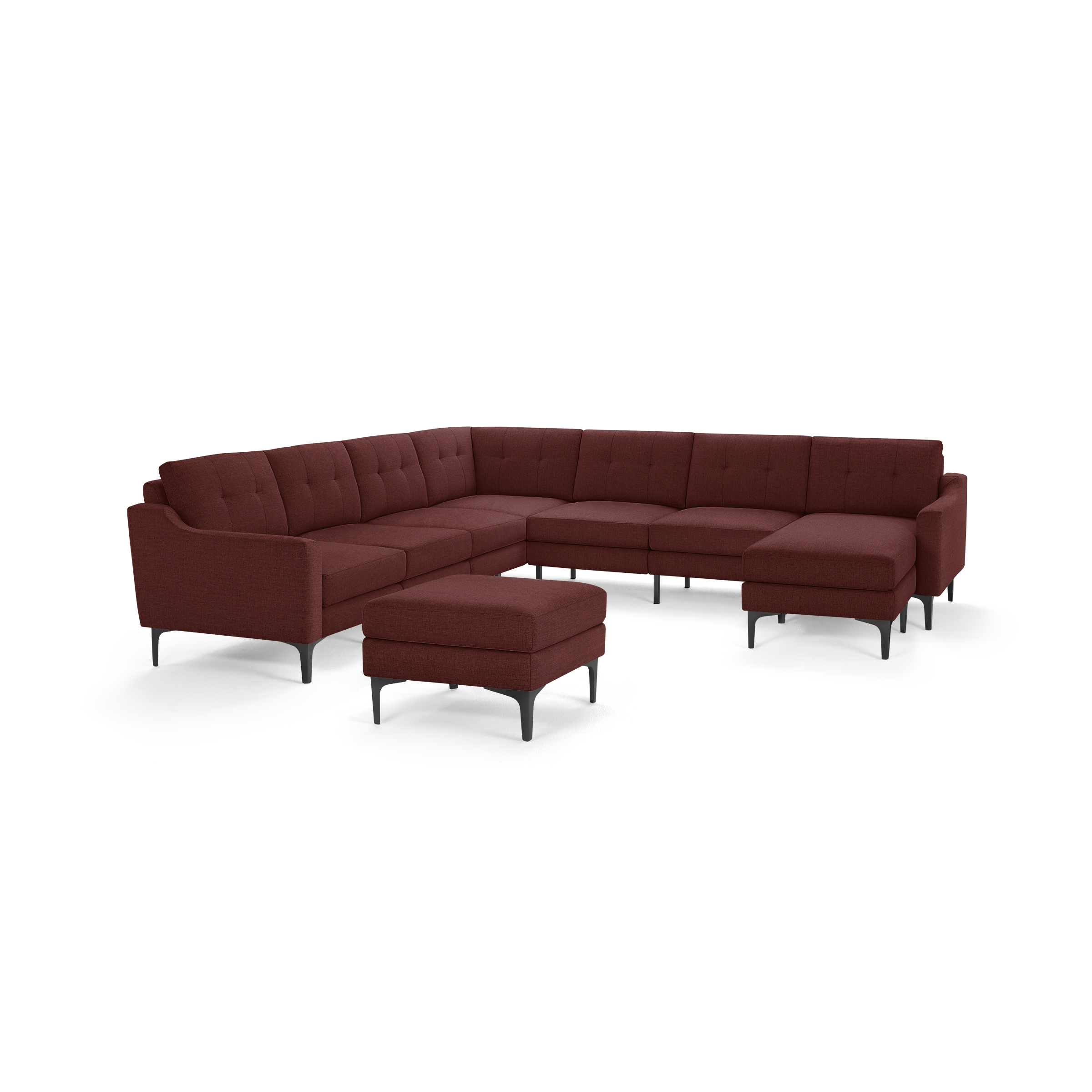 Large modern sectional sofa in deep red fabric with tufted cushions, slim black metal legs, and matching ottoman.