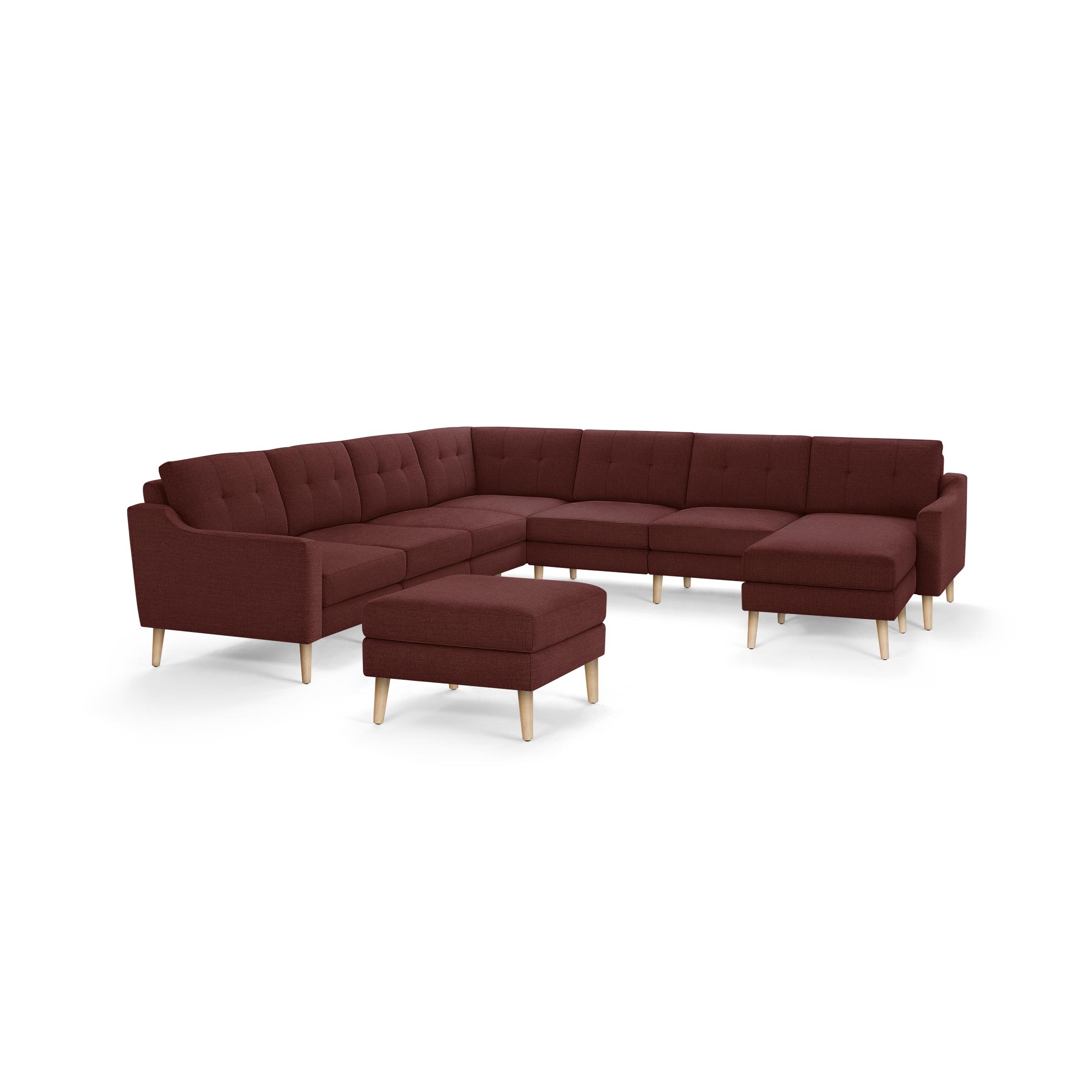 Large L-shaped sectional sofa in deep red fabric with tufted back cushions and light wooden legs, accompanied by a matching ottoman.