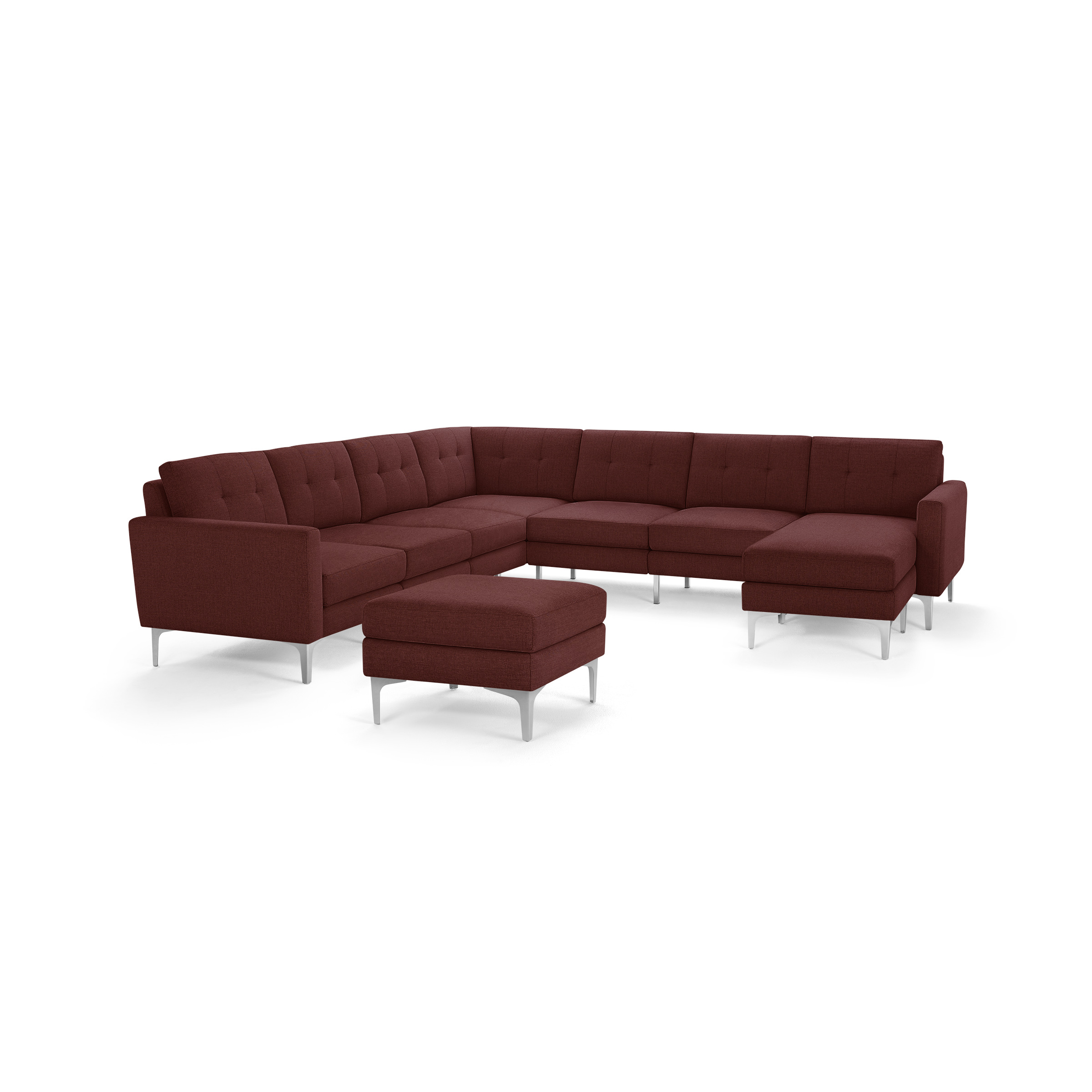 Modern L-shaped sectional sofa in deep burgundy fabric with tufted cushions and a matching ottoman, supported by sleek silver legs.