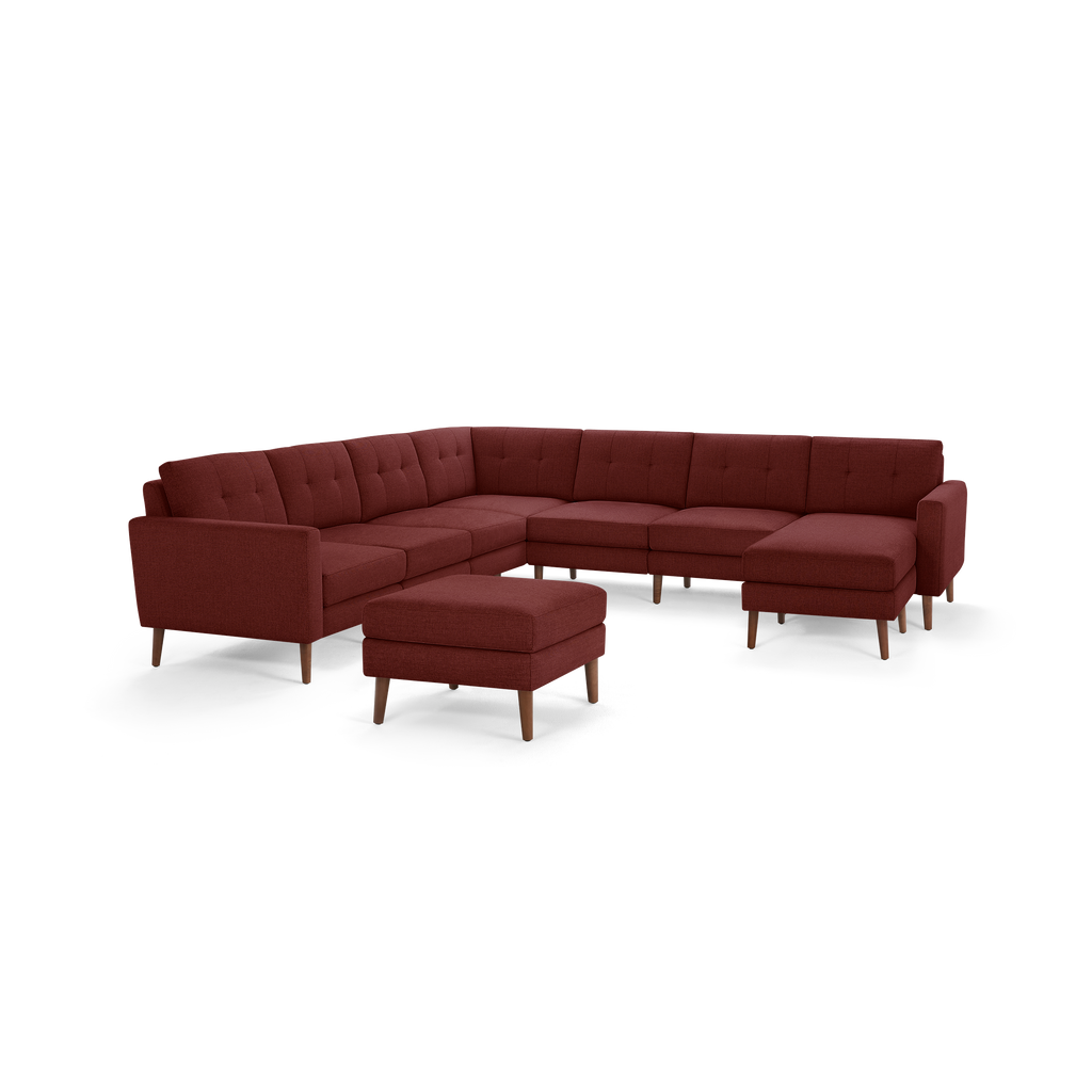 Large modern sectional sofa in deep red fabric with tufted cushions, wooden legs, and matching ottoman.