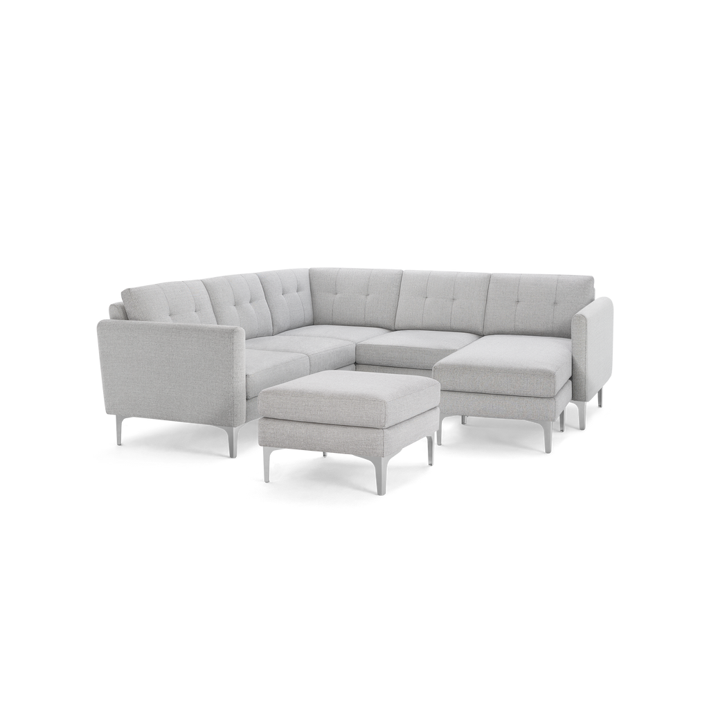 Light gray modern sectional sofa with tufted cushions, metal legs, and matching ottoman against black background.