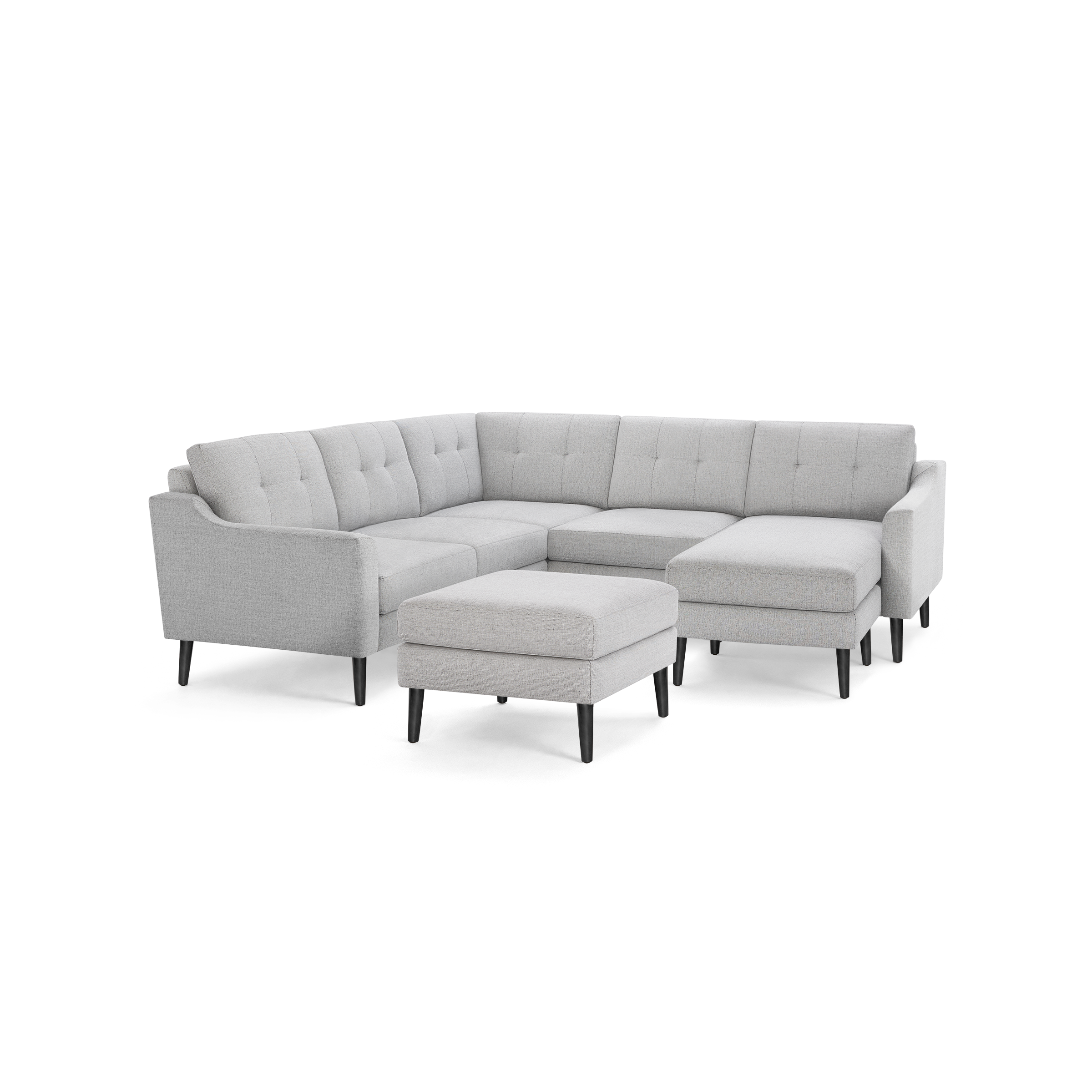 Light gray fabric sectional sofa with tufted back cushions and matching ottoman, supported by tapered dark wooden legs.