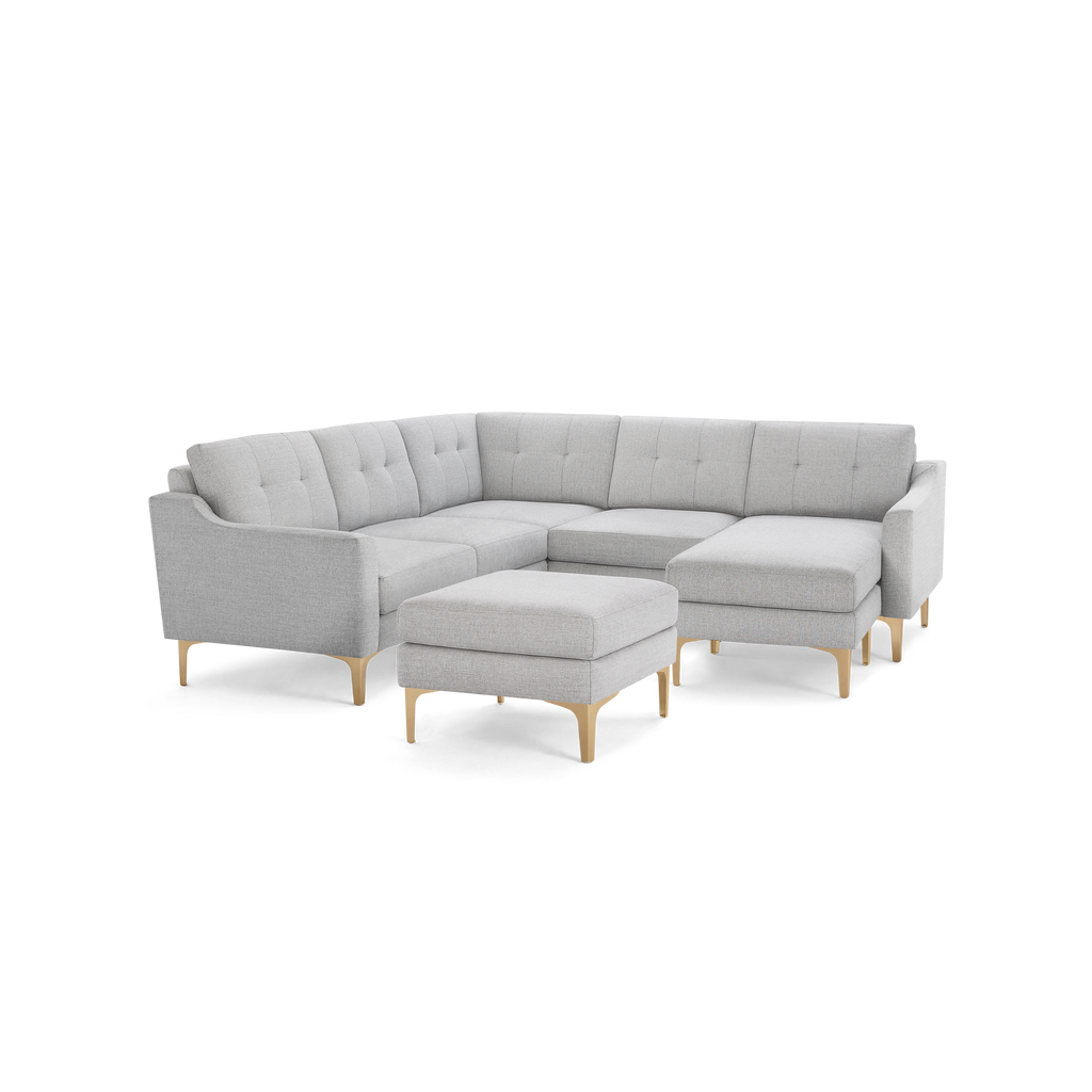 Light gray corner sectional sofa with tufted cushions, wooden legs, and a matching square ottoman.