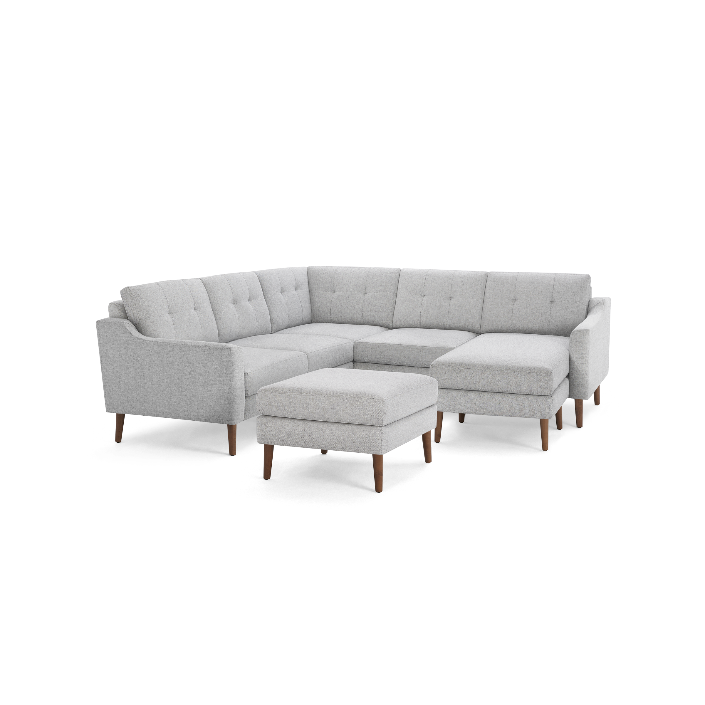 Light gray fabric sectional sofa with tufted cushions, wooden legs, and matching ottoman, showcasing a modern L-shaped design.