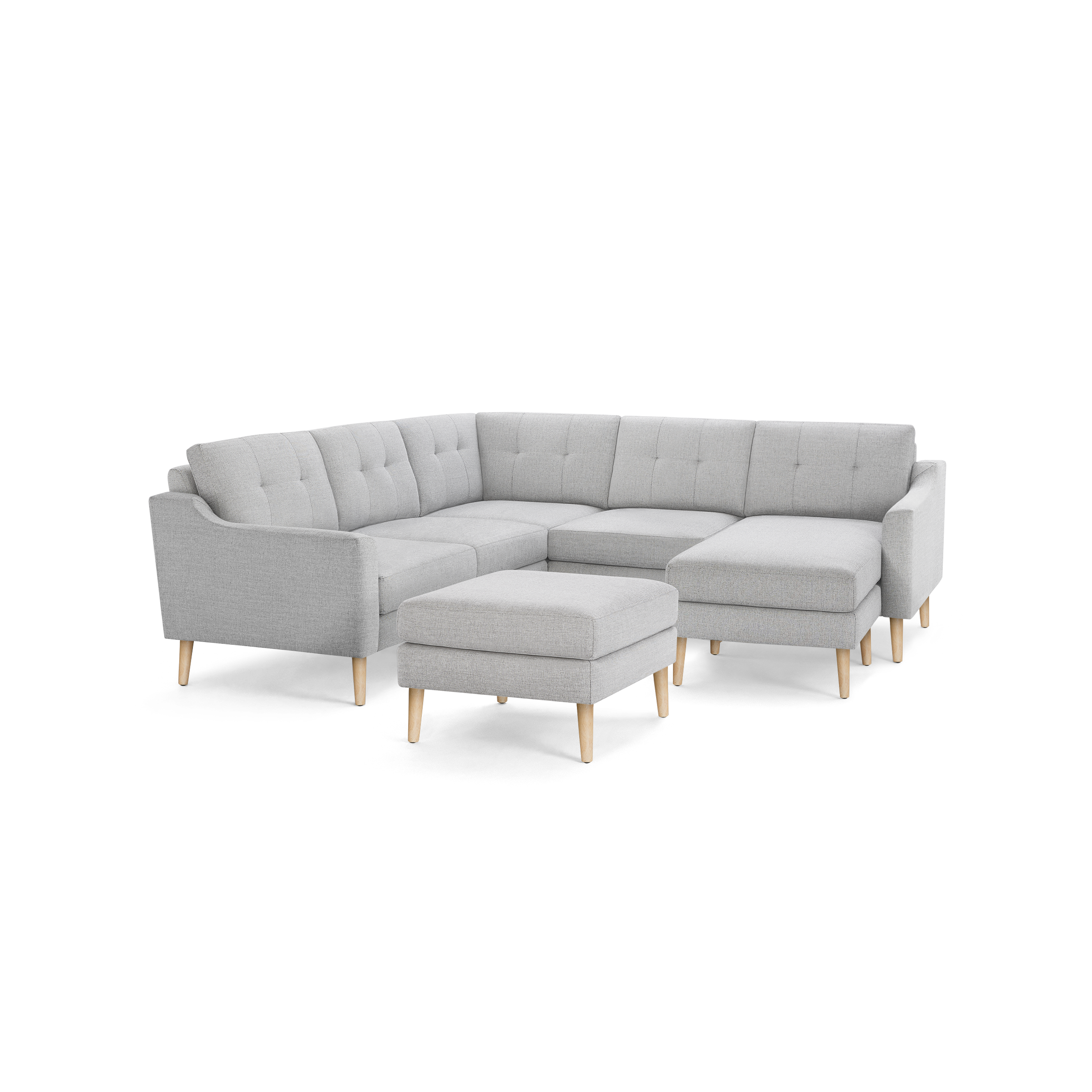 Light gray fabric sectional sofa with tufted cushions, wooden legs, and matching ottoman against black background.