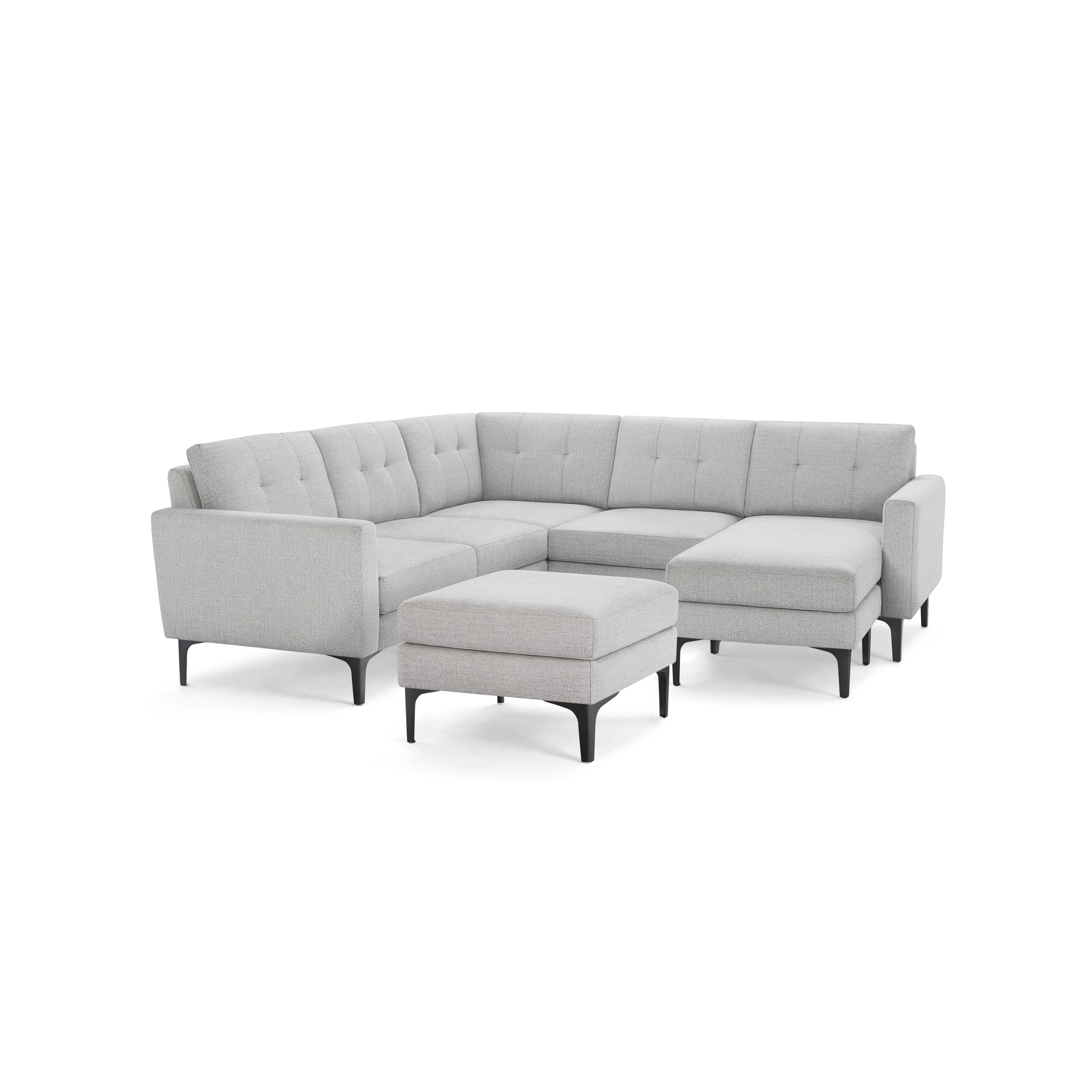 Light gray fabric upholstered L-shaped sectional sofa with tufted back cushions and matching ottoman on black slender legs.