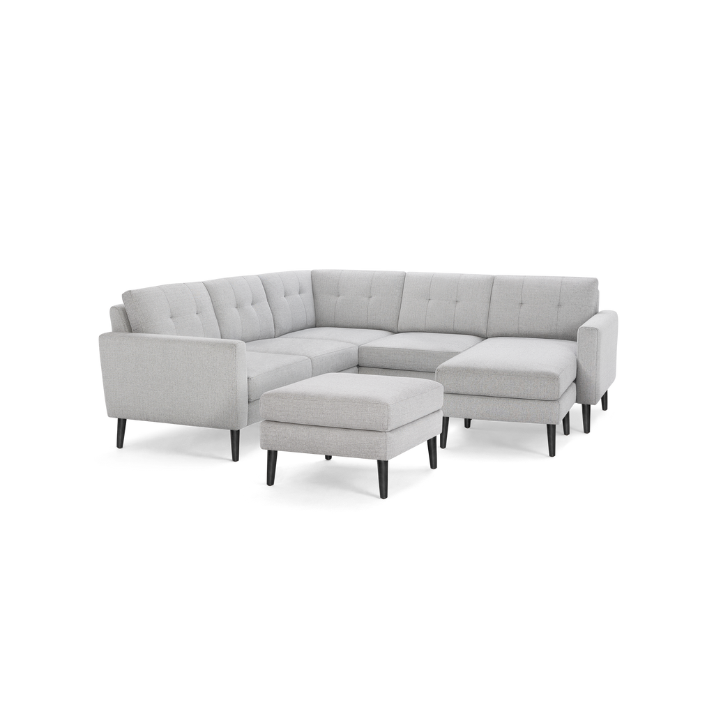 Light gray fabric sectional sofa with tufted back cushions, black tapered legs, and matching ottoman. Modern, minimalist design with clean lines.