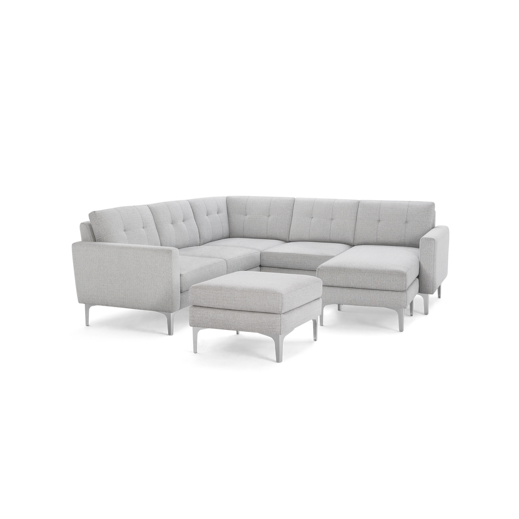 Light gray fabric sectional sofa with tufted back cushions, clean lines, metal legs, and a matching ottoman.