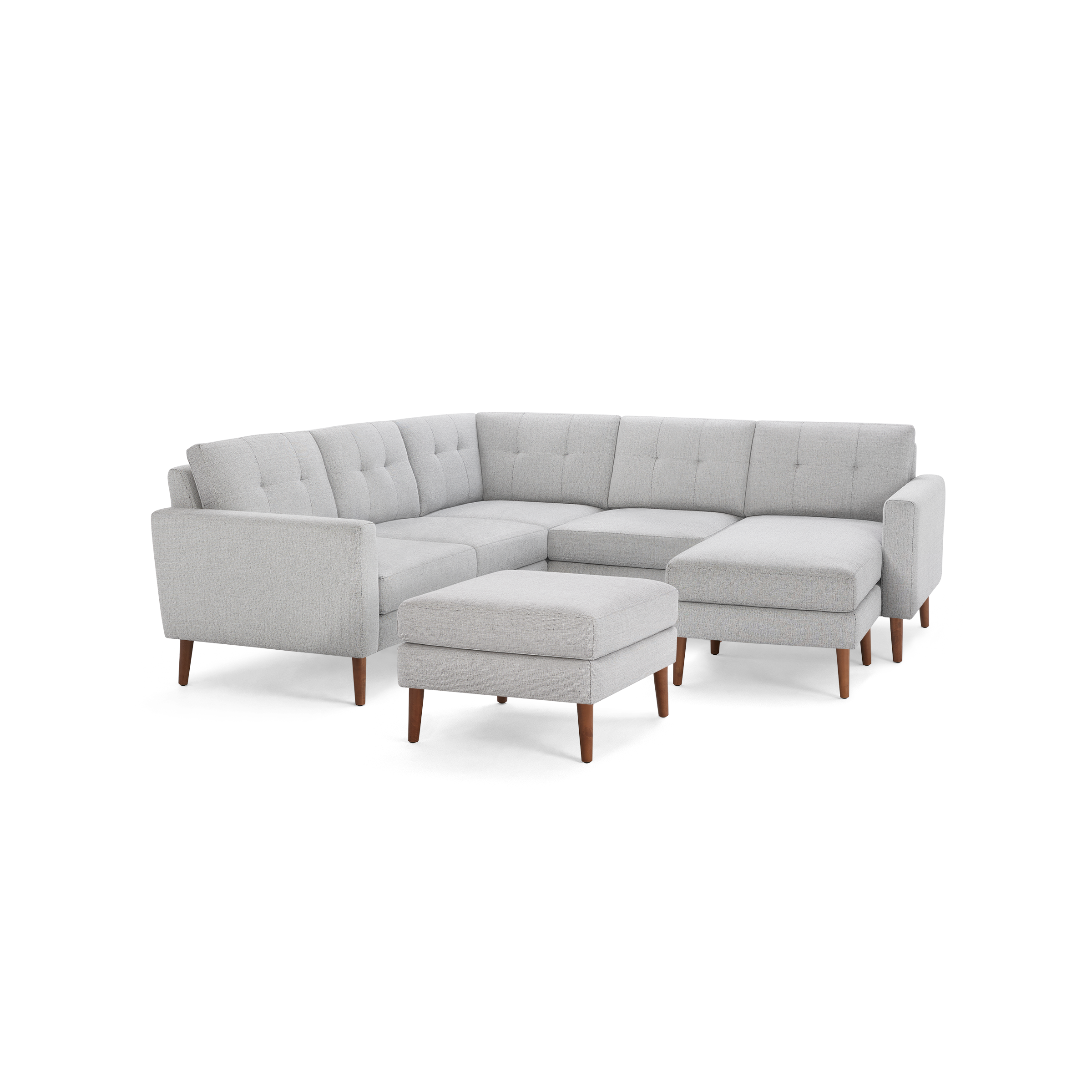Light gray L-shaped sectional sofa with tufted back cushions, wooden legs, and matching ottoman on a black background.