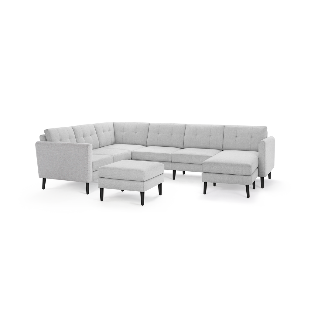 Light gray L-shaped sectional sofa with tufted backrests, black tapered legs, and matching ottoman on white background.