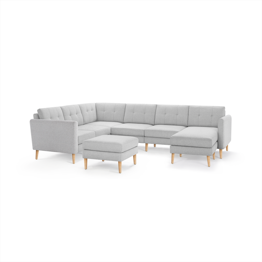 Light gray upholstered L-shaped sectional sofa with tufted backrests, wooden legs, and matching square ottoman.