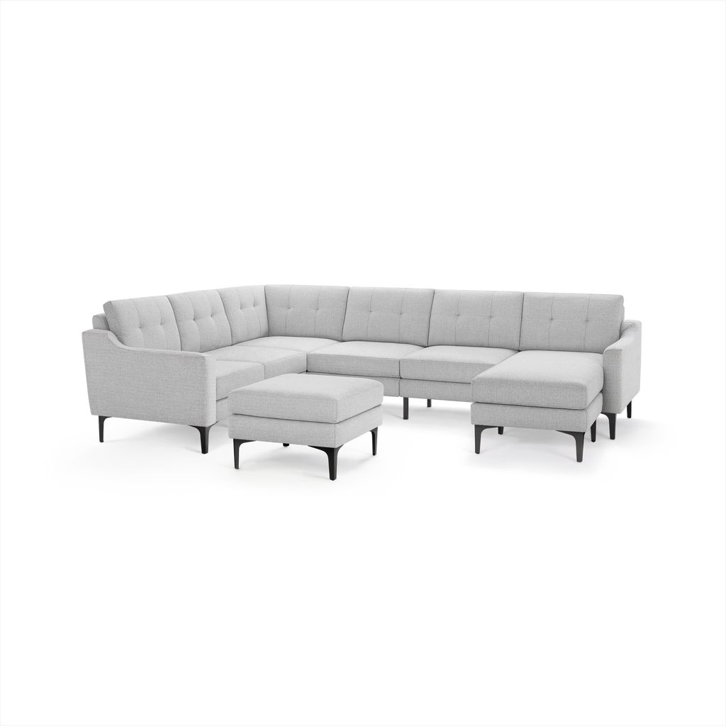 Light gray modern sectional sofa with tufted cushions, slim black legs, and a matching ottoman.