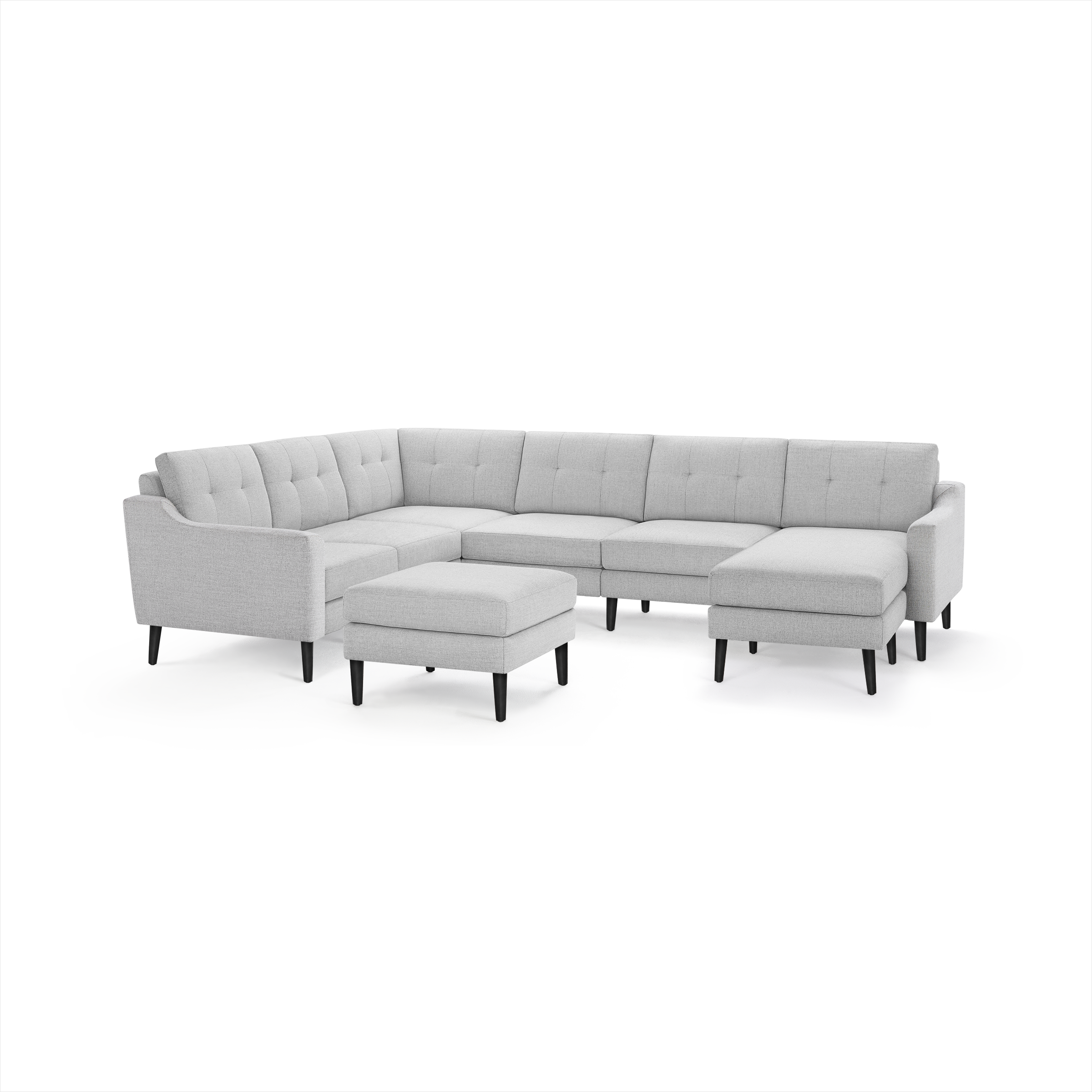 Light gray L-shaped sectional sofa with tufted back cushions, black wooden legs, and matching ottoman.