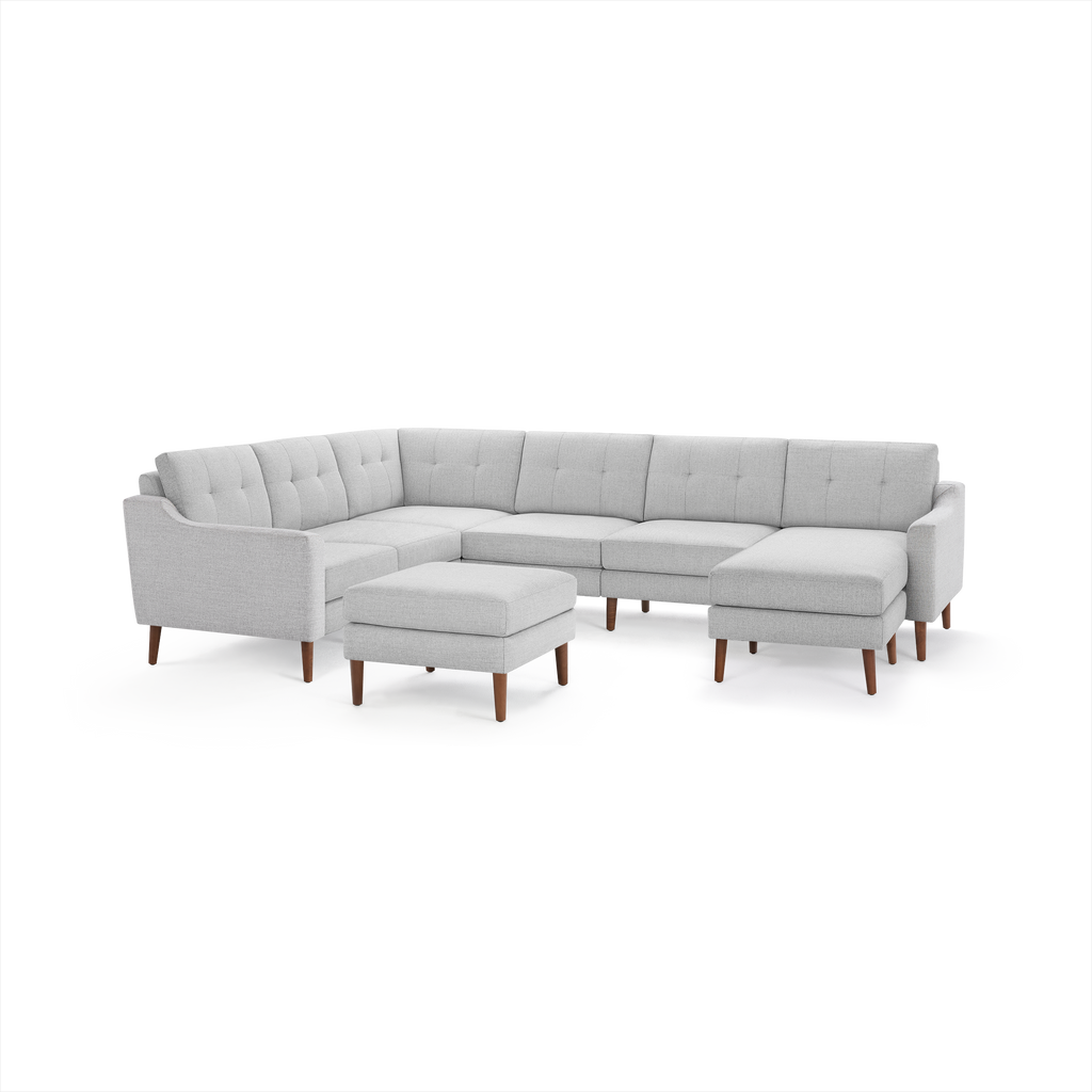Light gray fabric sectional sofa with tufted cushions, wooden legs, and matching ottoman against white background.