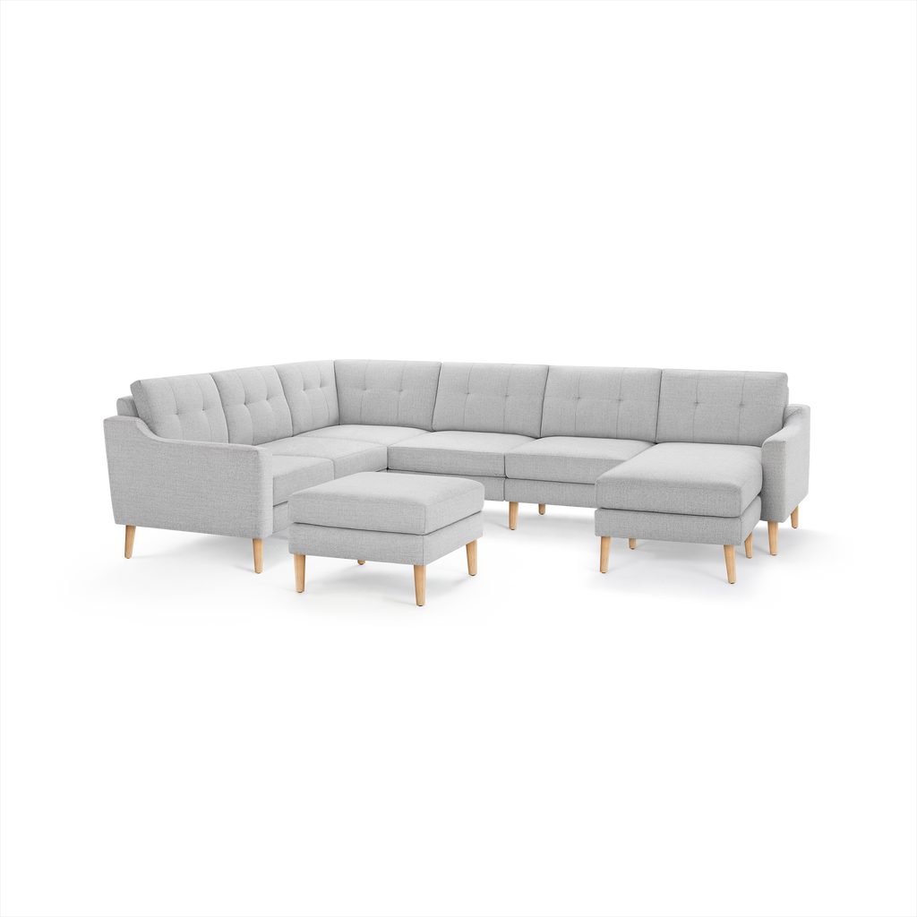 Light gray fabric L-shaped sectional sofa with tufted backrests and light wooden legs, including a matching ottoman.