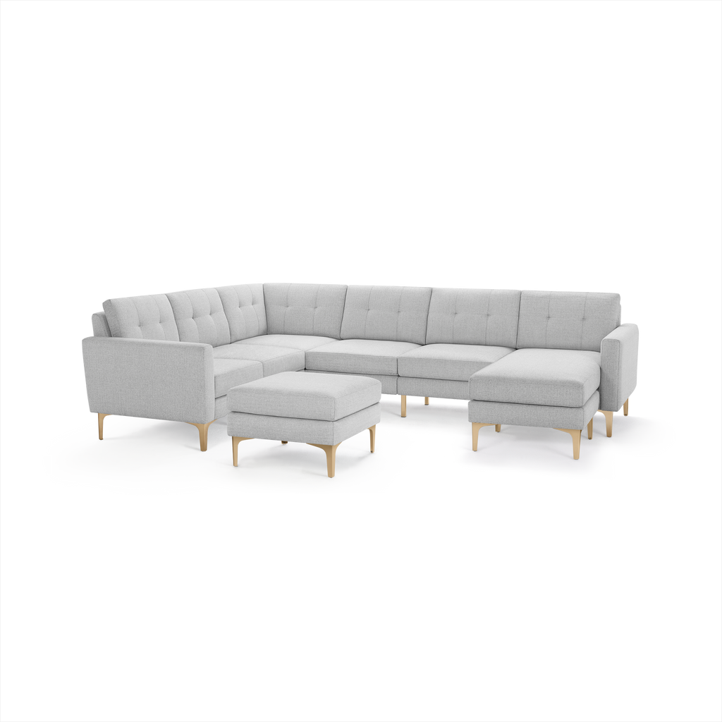 Light gray modern sectional sofa with tufted cushions, wooden legs, and matching ottoman, designed for spacious living rooms.