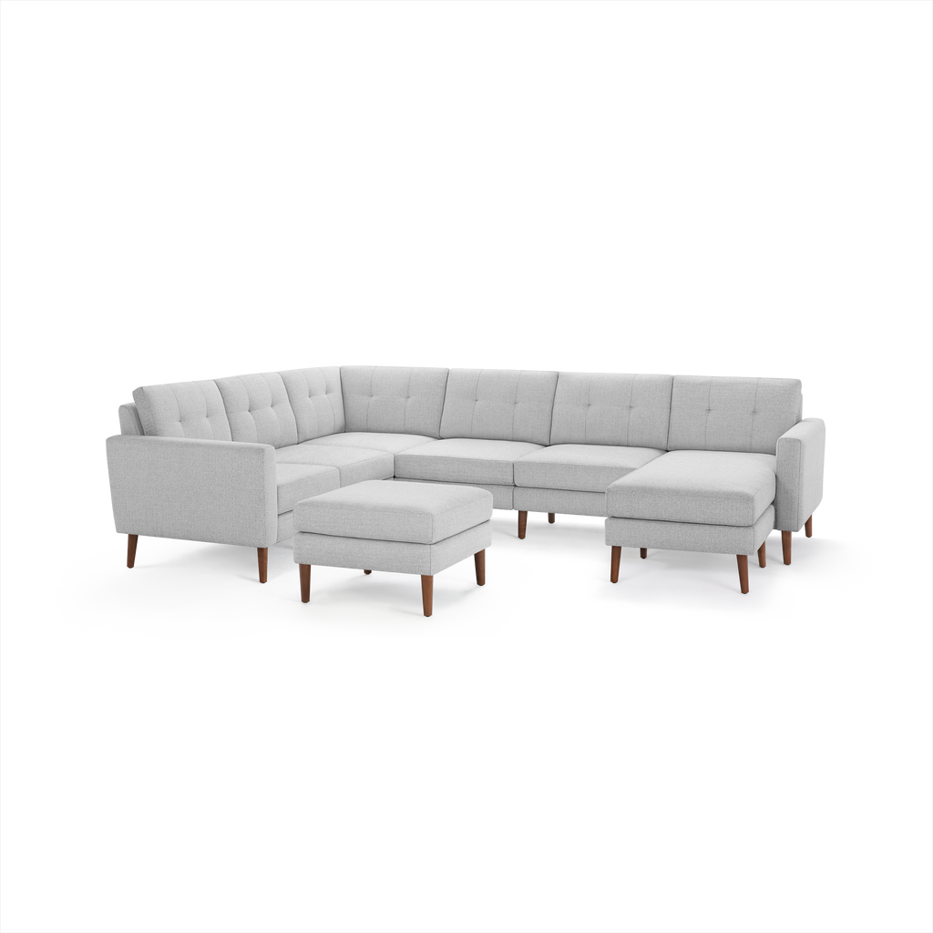 Light gray, modern sectional sofa with tufted cushions, wooden legs, and matching ottoman, upholstered in soft fabric.