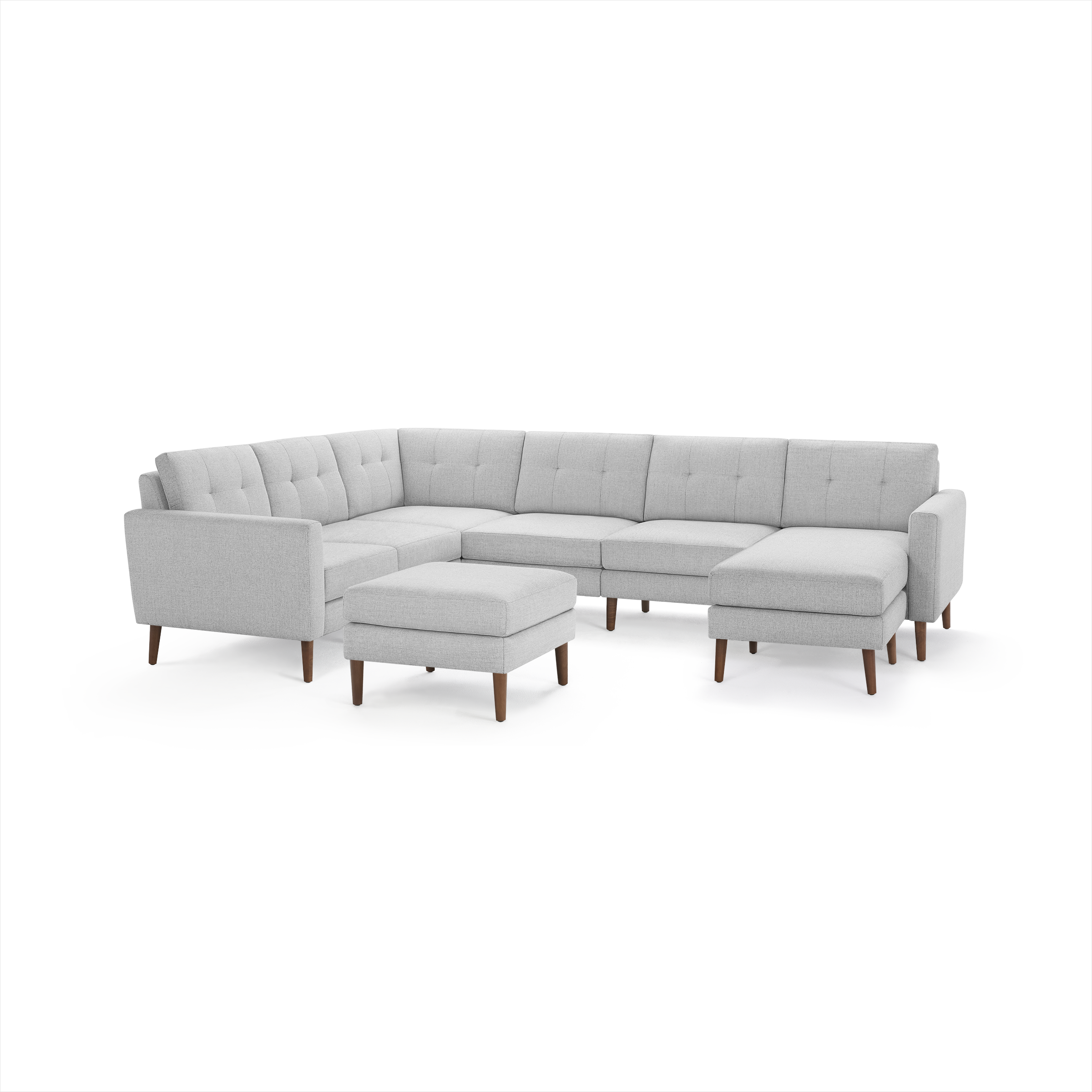 Light gray, modern sectional sofa with tufted cushions, wooden legs, and matching ottoman, upholstered in soft fabric.