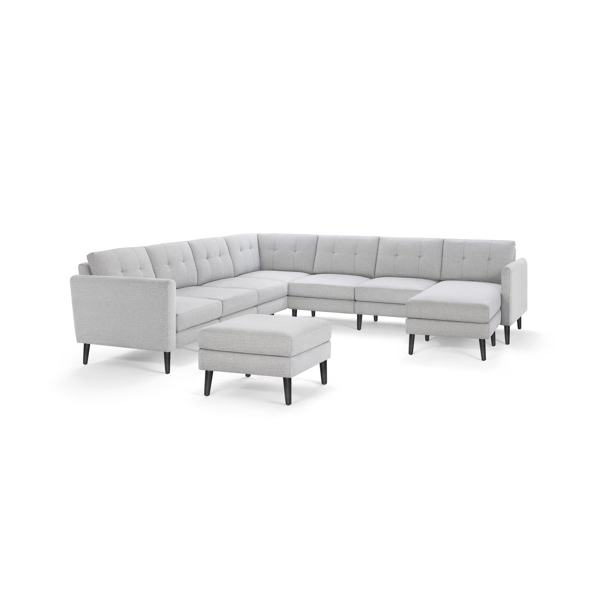 Light grey fabric L-shaped sectional sofa with tufted back cushions, angled arms, and matching ottoman on black tapered legs.