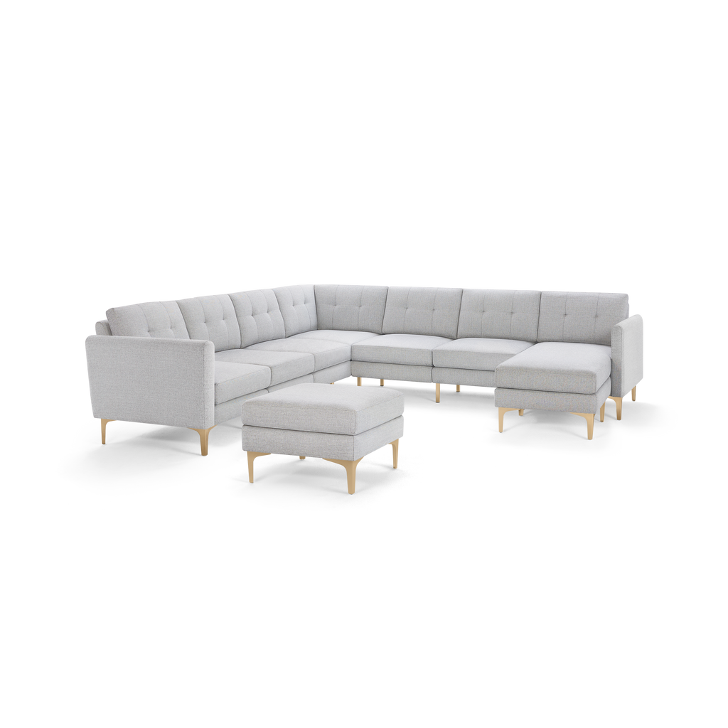 Light gray L-shaped sectional sofa with tufted cushions, wooden legs, and a matching square ottoman, modern style.