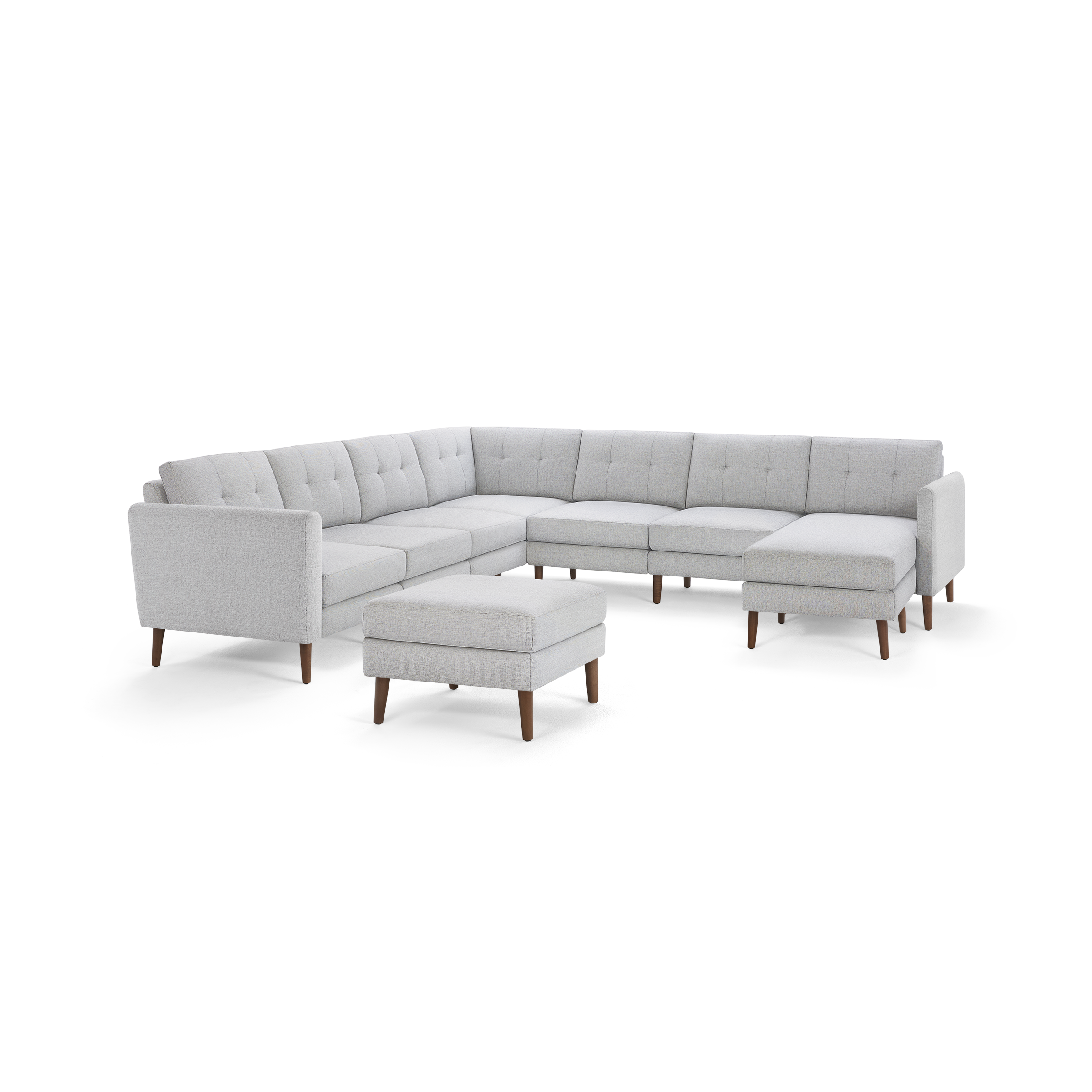Light grey fabric upholstered sectional sofa with tufted back cushions, wooden tapered legs, and a matching rectangular ottoman.
