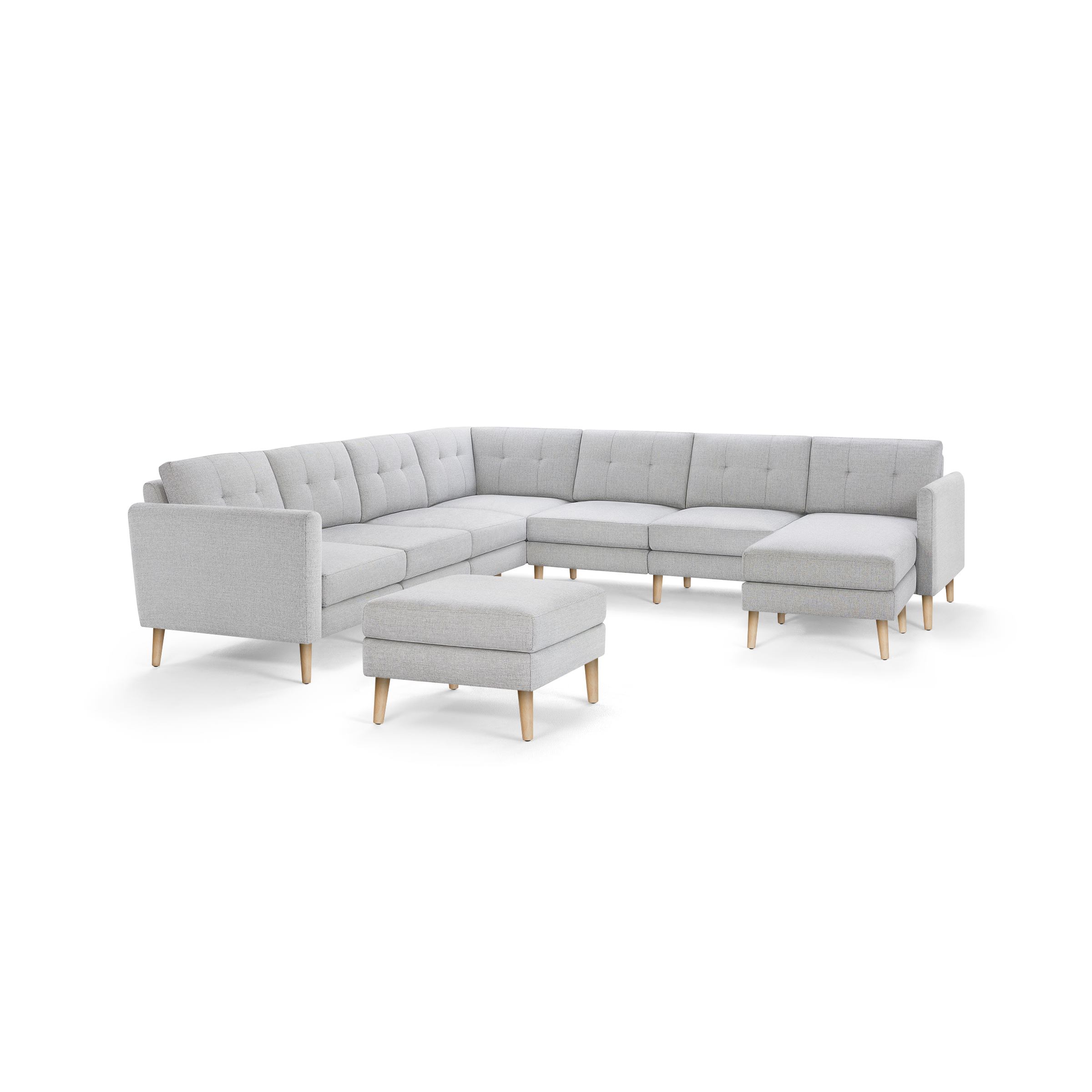 Light grey L-shaped sectional sofa with tufted back cushions and matching ottoman, featuring wooden legs.