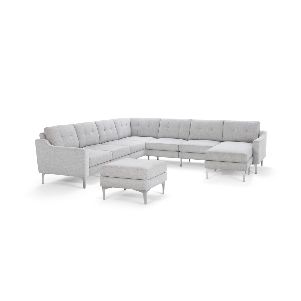 Light gray L-shaped sectional sofa with tufted cushions and matching ottoman, supported by sleek metal legs.