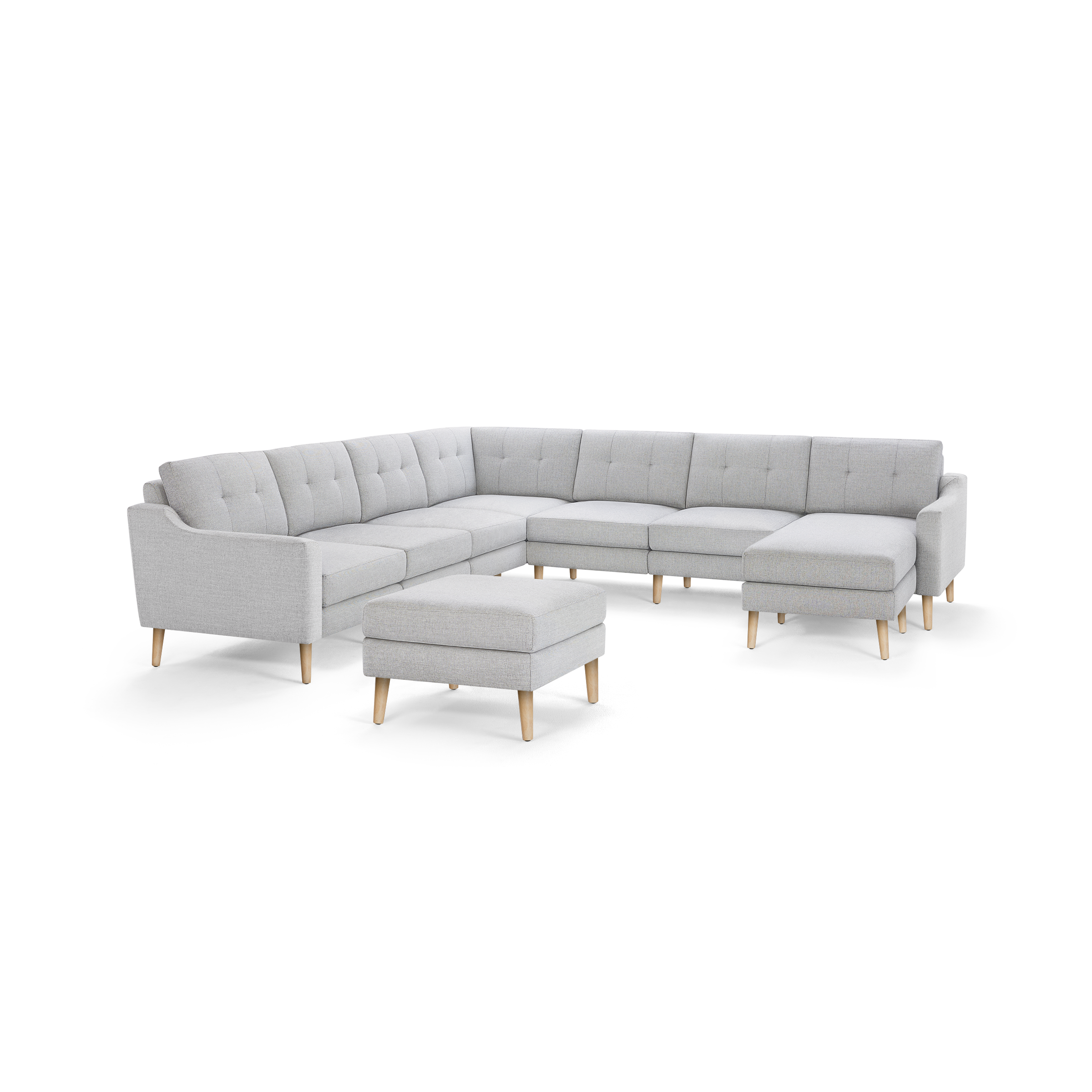 Light gray L-shaped sectional sofa with tufted cushions and light wooden legs, accompanied by a matching ottoman.