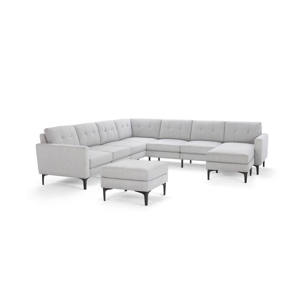 Light gray L-shaped sectional sofa with tufted back cushions and black metal legs, accompanied by a matching ottoman.
