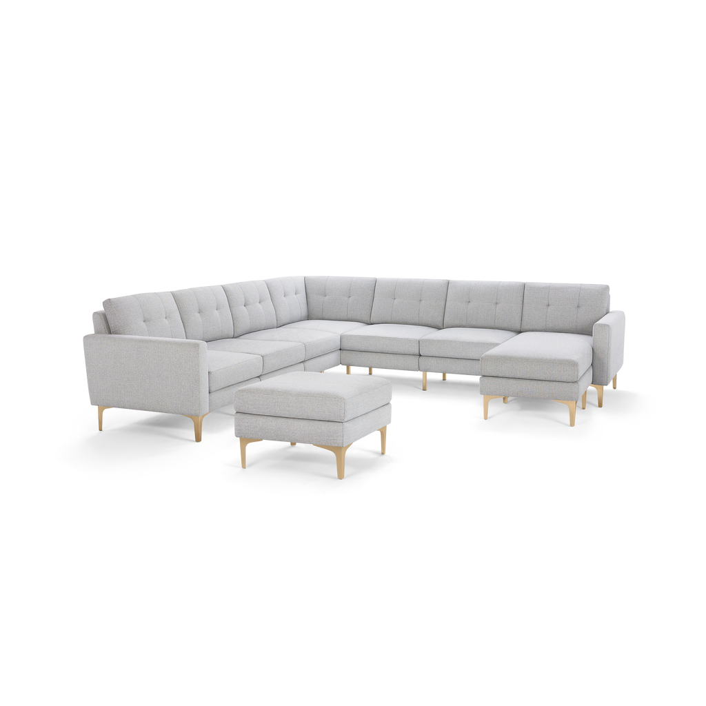 Light gray fabric sectional sofa with tufted back cushions, wooden legs, and matching ottoman on white background.