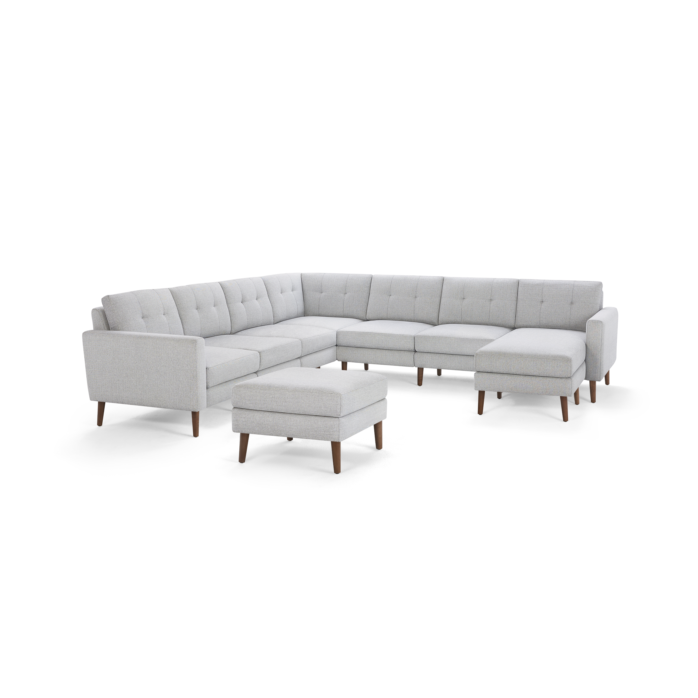 Light gray fabric sectional sofa with tufted back cushions, wooden legs, and matching ottoman, modern mid-century design.