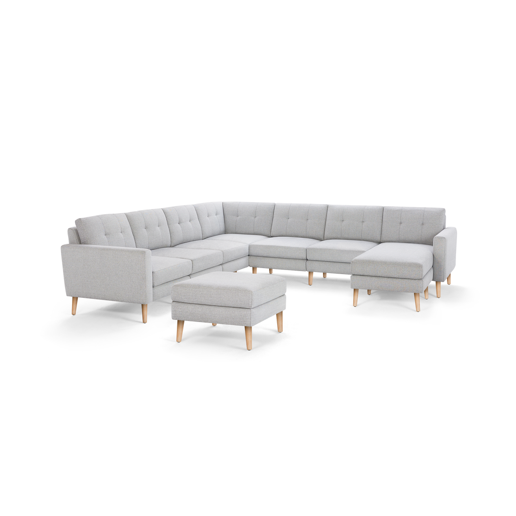 Light gray upholstered L-shaped sectional sofa with tufted back cushions and wooden legs, including a matching square ottoman.
