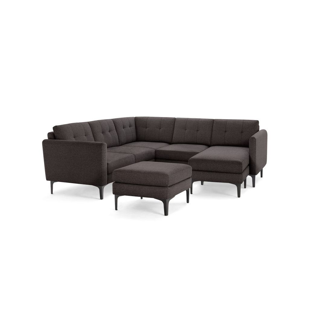 Dark gray fabric sectional sofa with tufted back cushions and matching ottoman, supported by black metal legs.