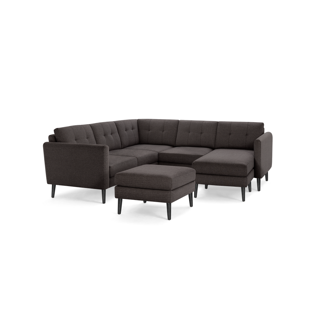 Dark gray modern L-shaped sectional sofa with tufted cushions and matching ottoman, featuring slim black legs.