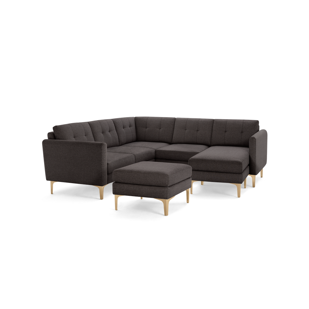 Dark gray tufted fabric sectional sofa with light wooden legs, including a matching ottoman.