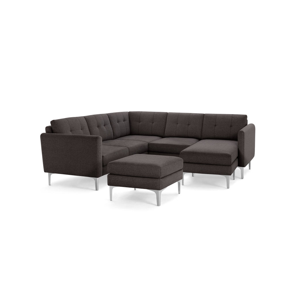 Dark gray L-shaped sectional sofa with tufted cushions, sleek armrests, and metal legs, including a matching ottoman.